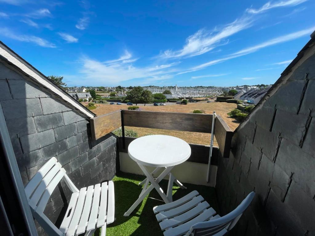 a balcony with a white table and chairs and a view at APPARTEMENT VUE PORT CROUESTY in Arzon
