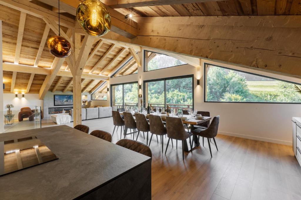 a dining room with a table and chairs and large windows at Chalet des Granges 12 personnes Spa et cinéma in Morzine