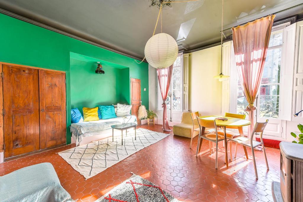 a living room with green walls and a table and chairs at Cool charming appartment in historic forcalquier in Forcalquier
