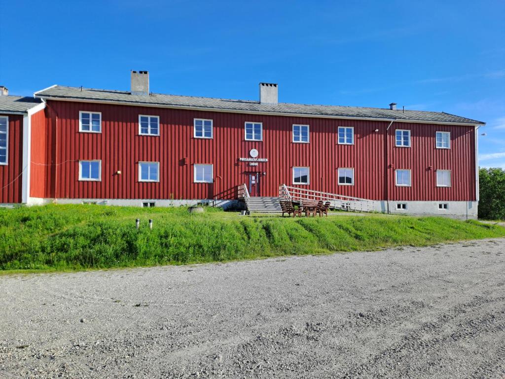 a red building with a bench in front of it at Porsangerfjorden Lodge in Børselv