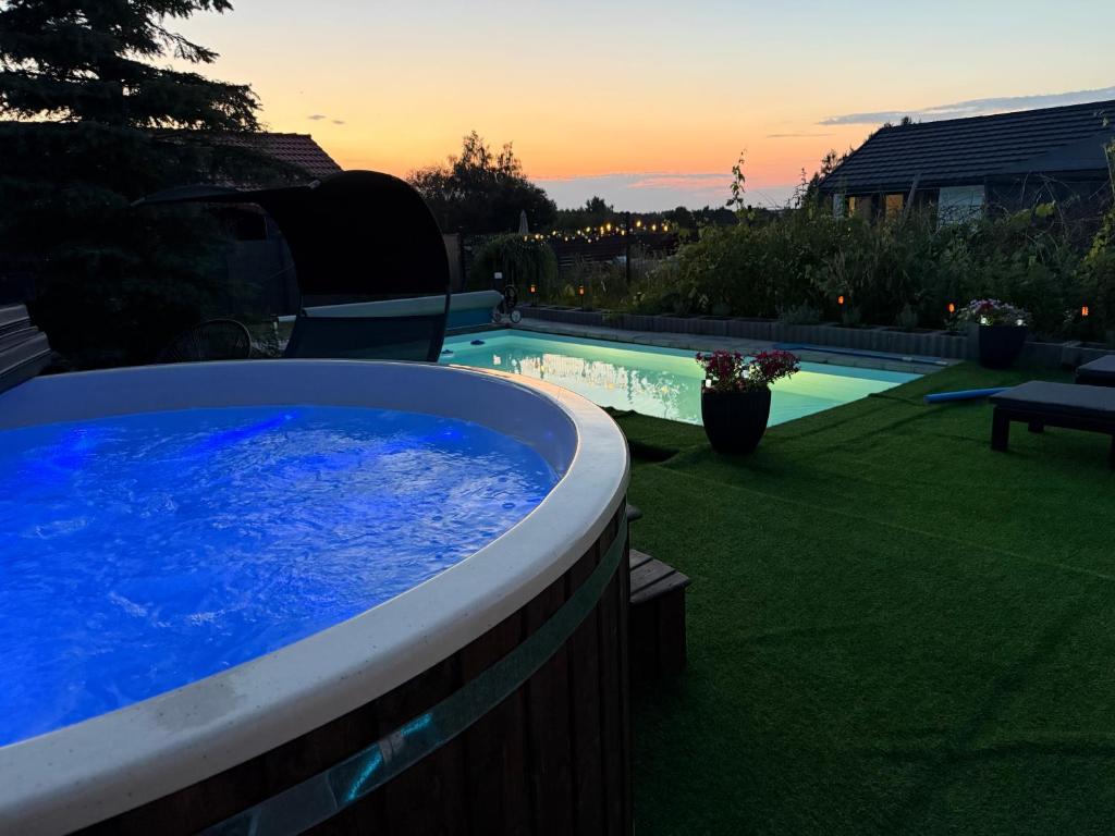 a hot tub in a yard with a sunset in the background at Koniec Świata dom 84m2 z balią i basenem na wyłączność in Mikołajki