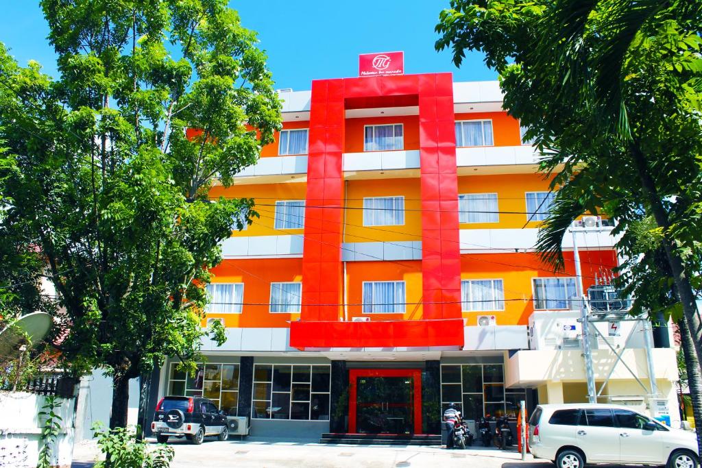 Maleosan Inn Manado Hotel في مانادو: مبنى برتقالي وبيض وفيه احمر
