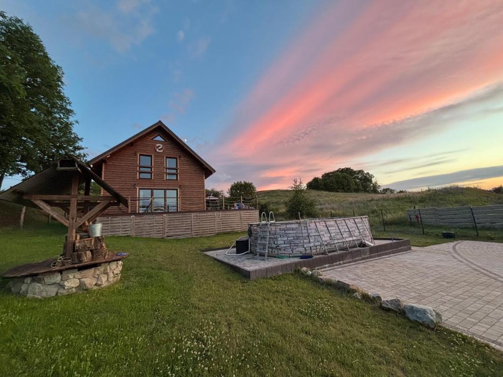 a house on a field with a rainbow in the sky at Woodstock in Krajnik Dolny