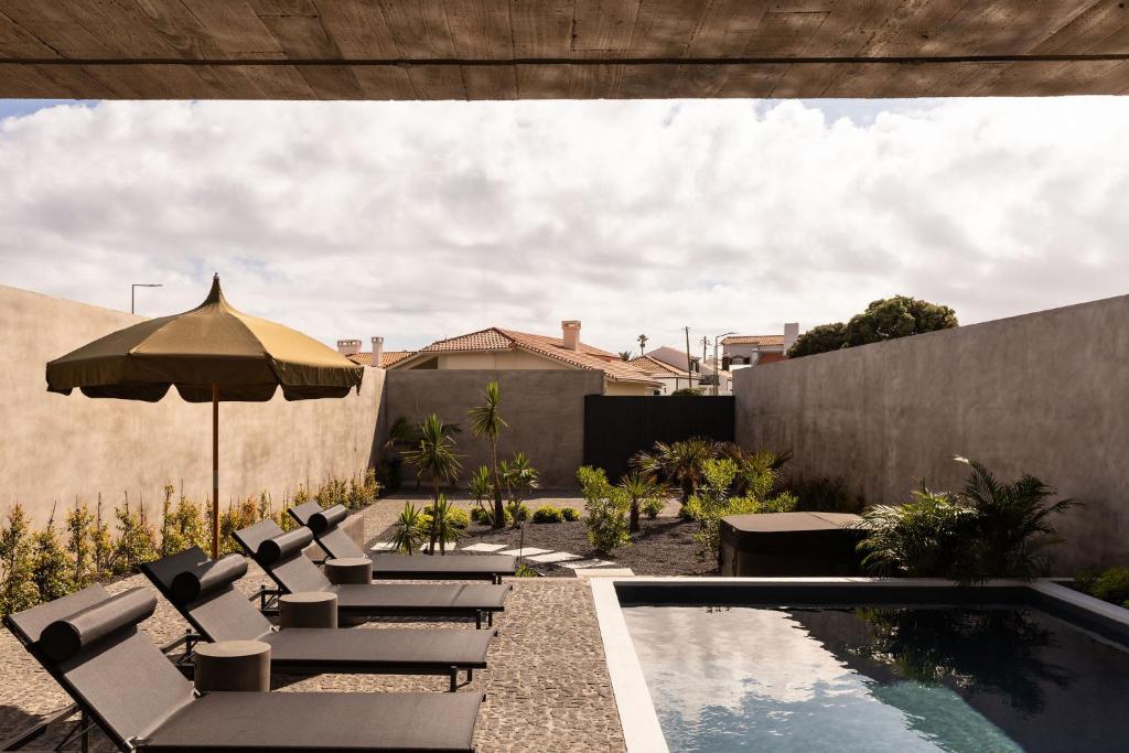 a patio with chairs and an umbrella next to a pool at Residence - Signature Villas in Lagoa