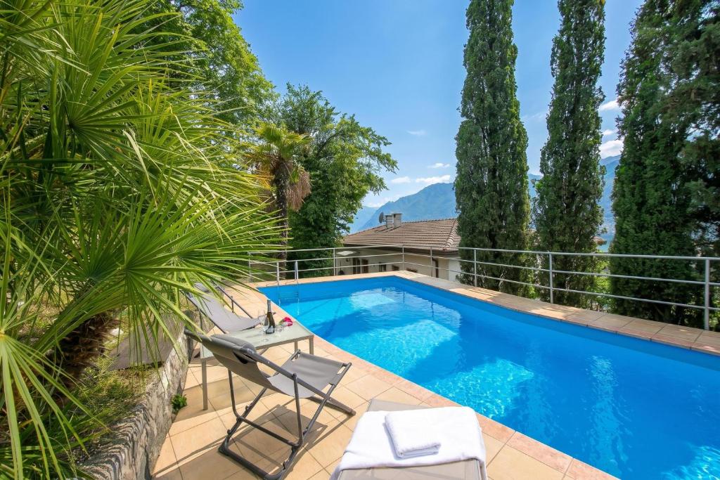 a swimming pool with two chairs and trees at Villa Panorama with Private Pool in Nago-Torbole