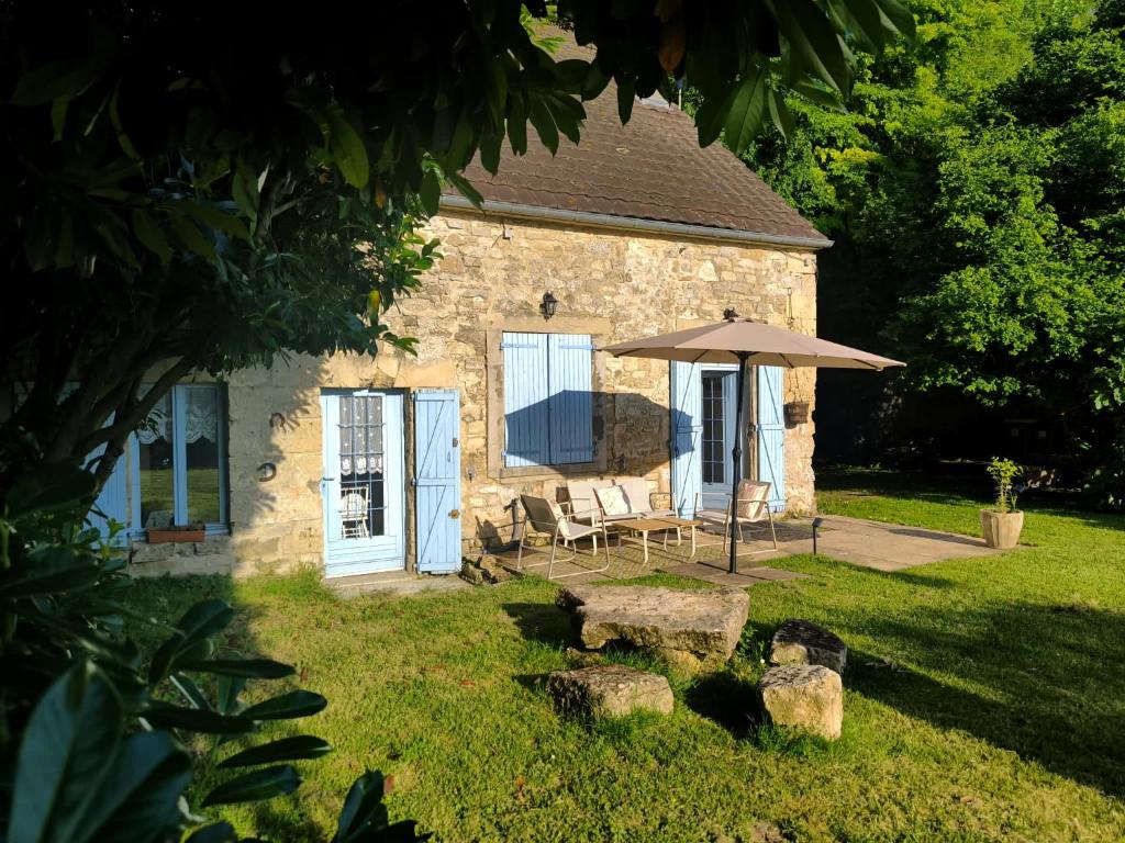 a stone house with a table and an umbrella at La Maison bleue Paissy in Paissy