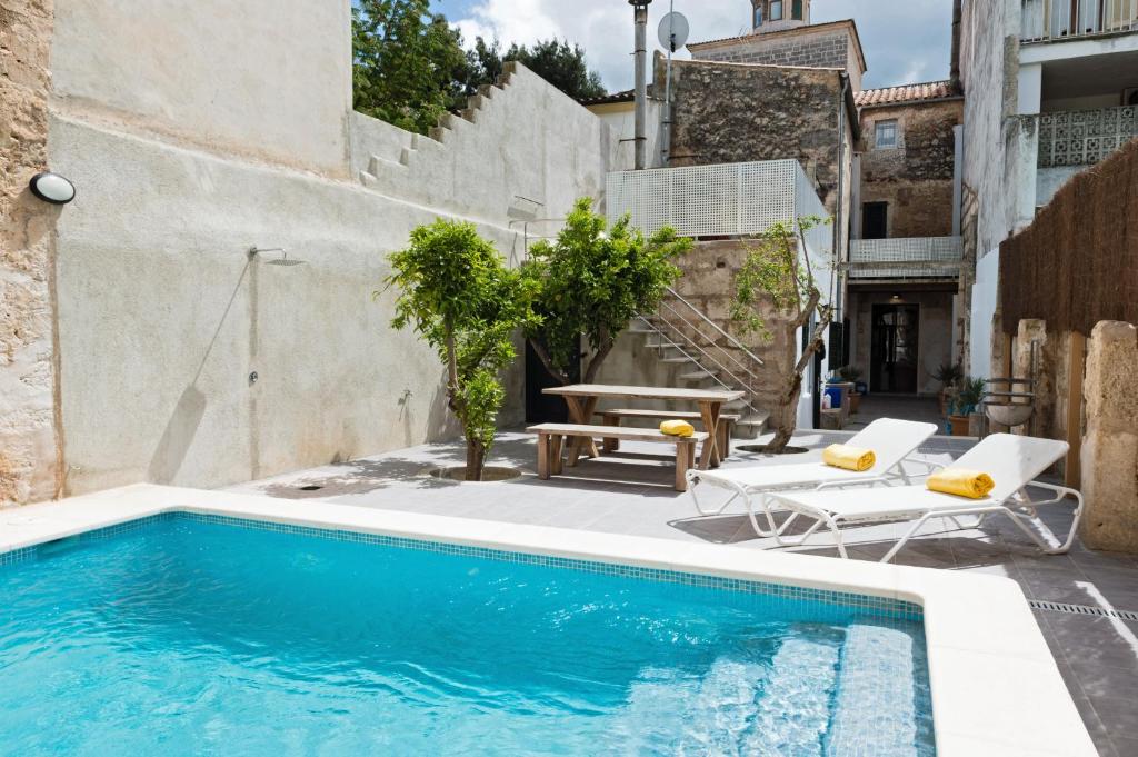 a pool with two chairs and a table next to a building at Villa Ca na Marrona - Sunset Villa Campanile in Sa Pobla