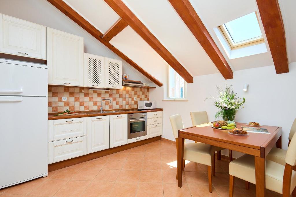a kitchen with white cabinets and a wooden table at Hedera Estate Hedera A34 in Dubrovnik