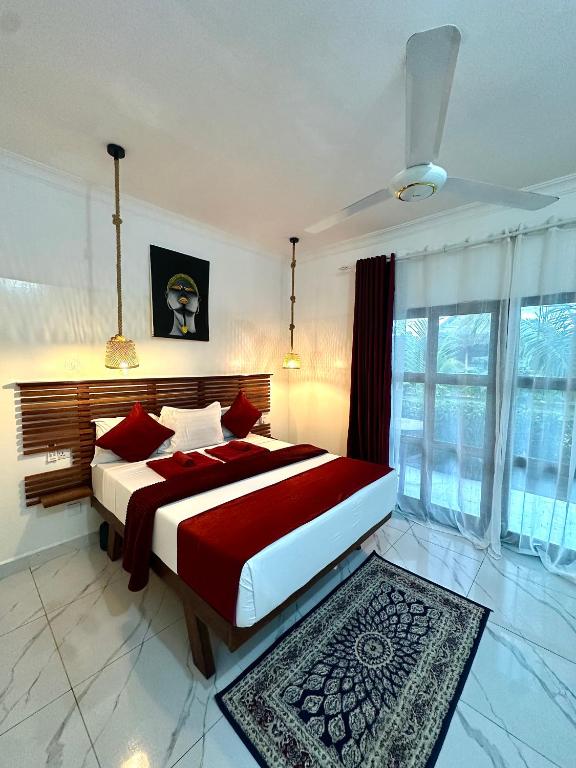 a bedroom with a large bed with red pillows at Kendwa Crystal Coast Hotel in Kendwa