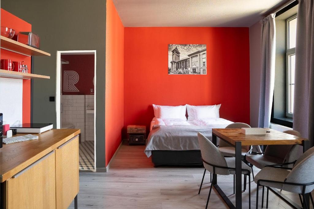 a bedroom with an orange wall with a bed and a table at Revelton Ostrava in Ostrava