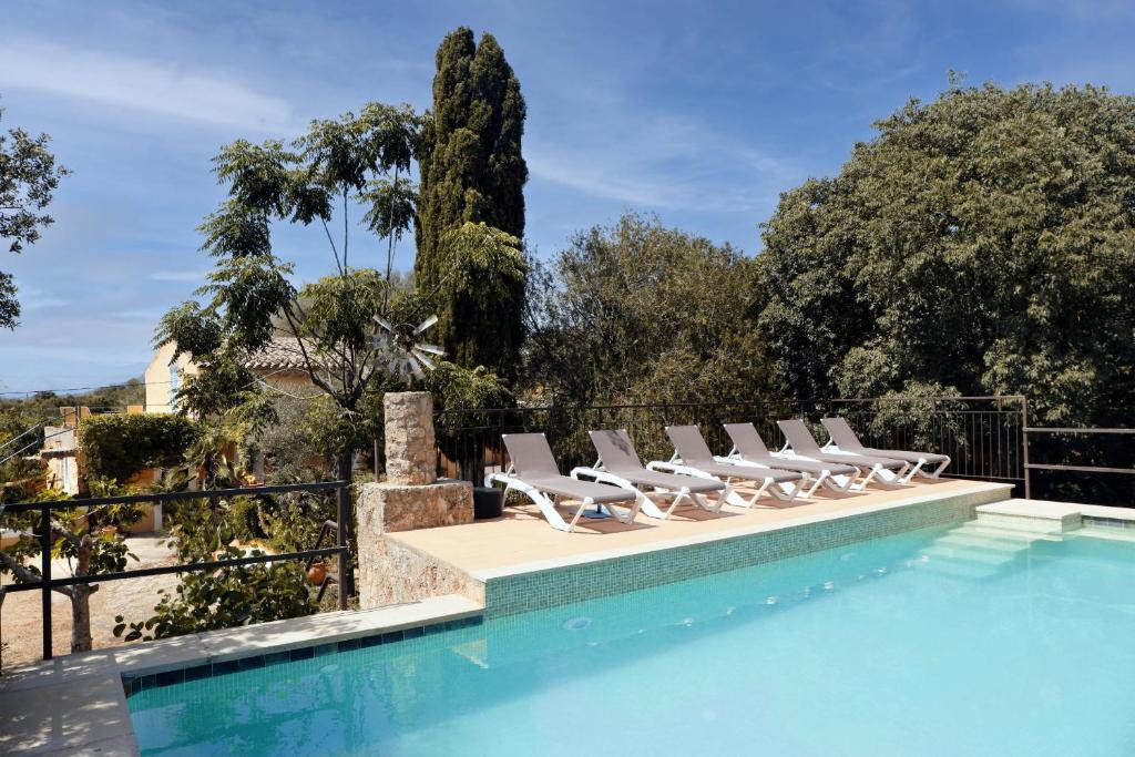 a row of lounge chairs next to a swimming pool at Sunset private Eco-Villa Can Vey in Inca