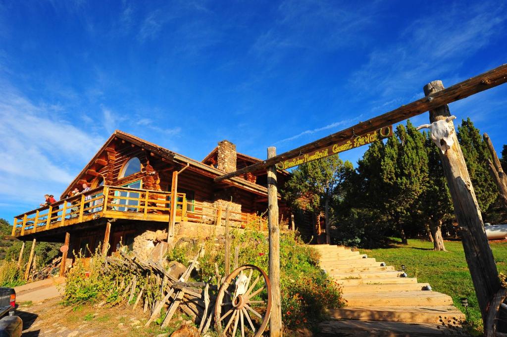 Cette cabane en rondins comprend une terrasse couverte en bois et des escaliers. dans l'établissement Boulder Mountain Guest Ranch, à Boulder Town