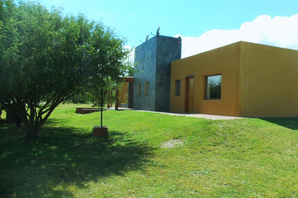 a building with a tree in the grass next to a building at Complejo cabañas Portal Uritorco in Charbonier