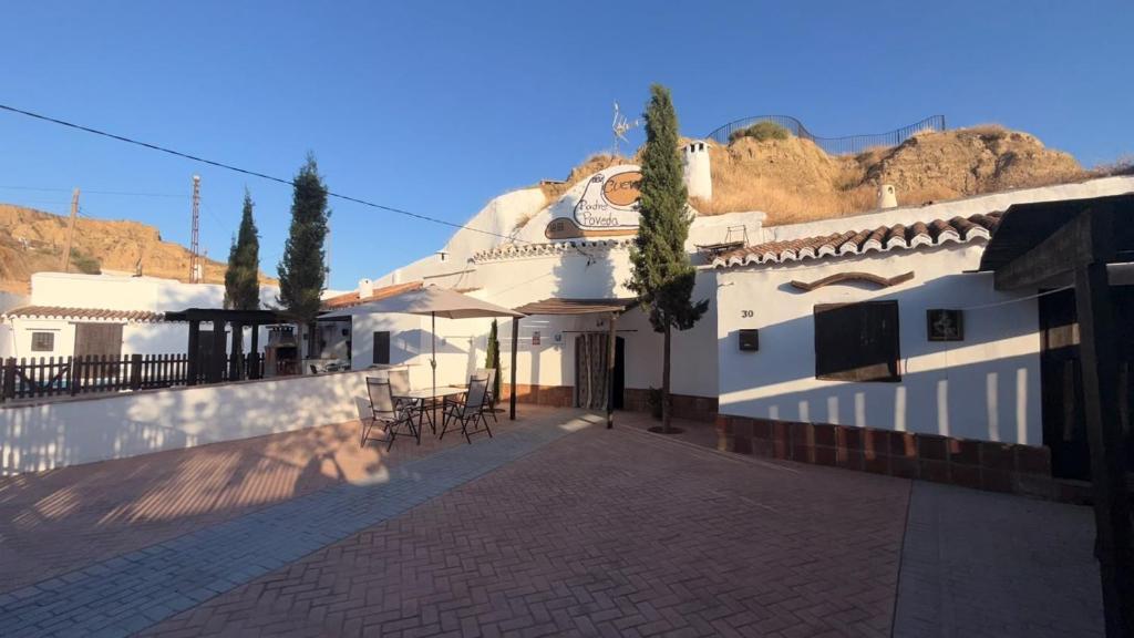 a white building with a patio with tables and chairs at Cuevas Padre Poveda in Guadix