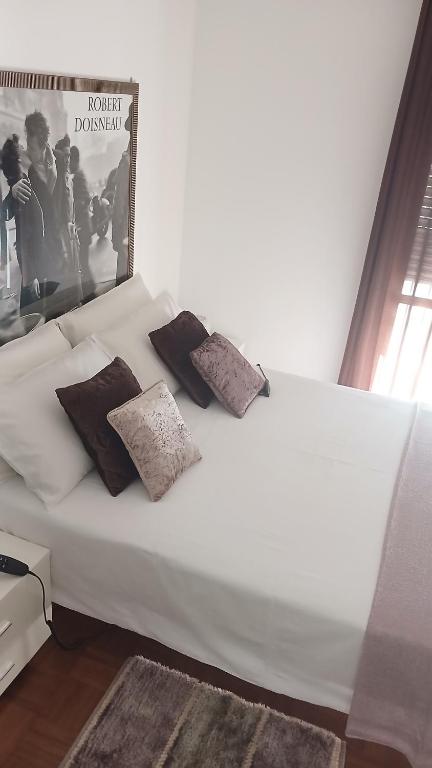 a white bed with pillows and a poster of a movie at "Da Zia House Comfort e Relax vicino a Torino" in Brandizzo