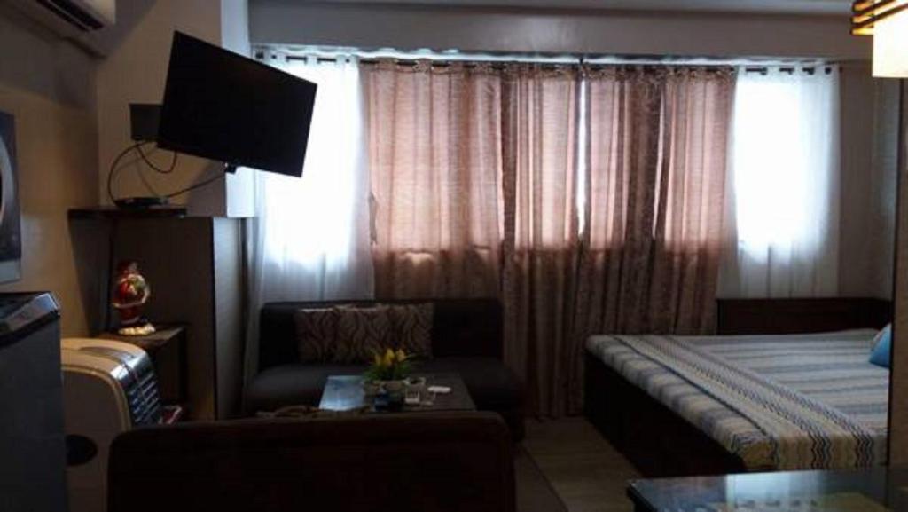 a bedroom with a bed and a couch and a television at Montecarlo Sta Lucia 6J&k in Manila