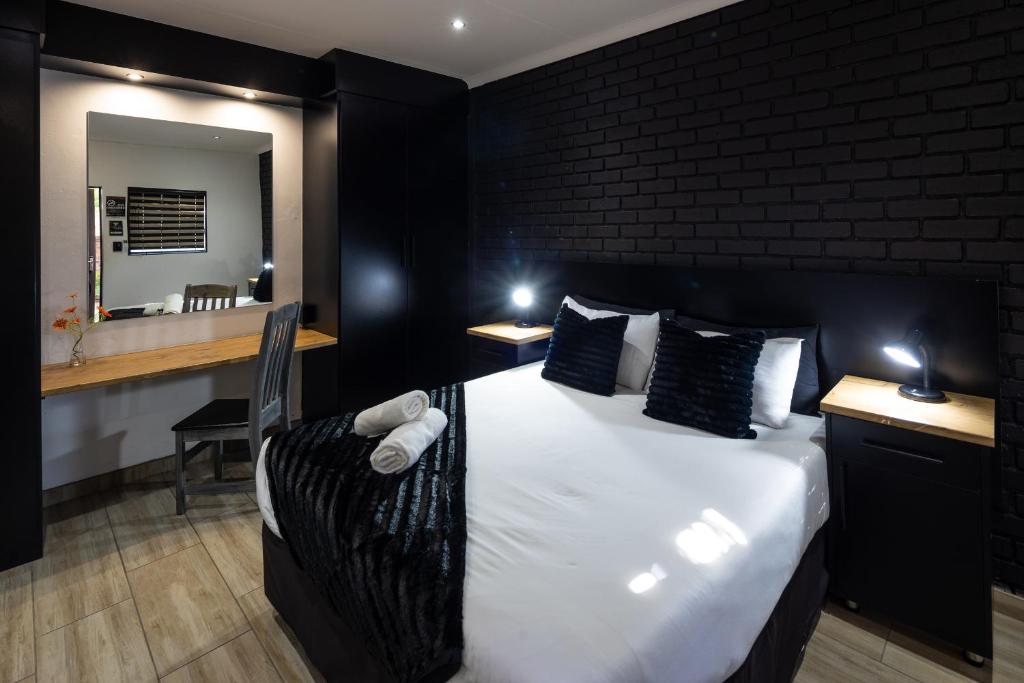 a bedroom with a bed and a desk with a mirror at Fox Inn Guesthouse Lephalale in Lephalale
