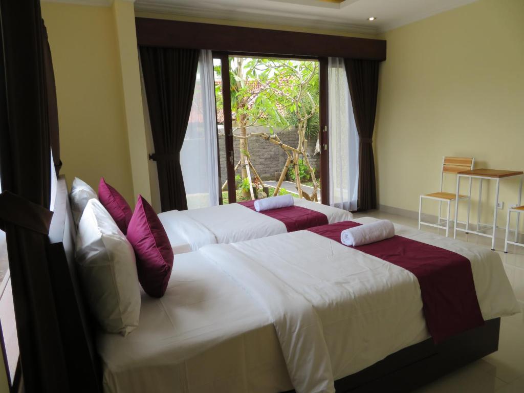 2 letti in una camera da letto con finestra di Odah Ayu Guest House ad Ubud