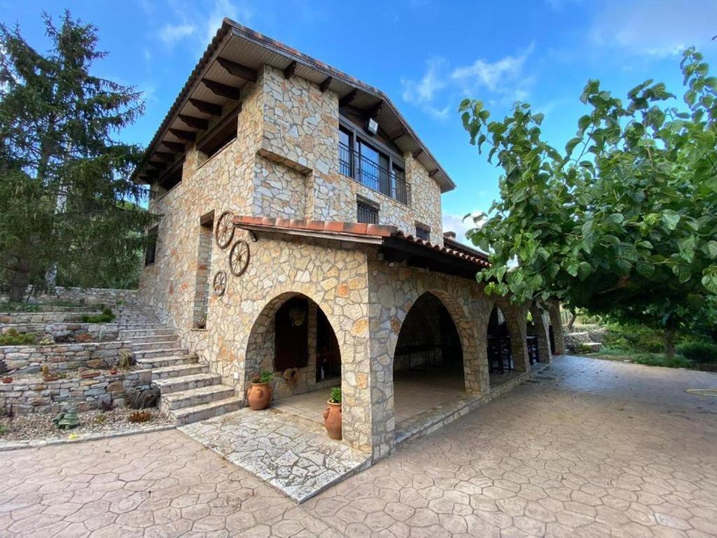 a large stone house with a patio and stairs at Masía de piedra con piscina in Riudecols