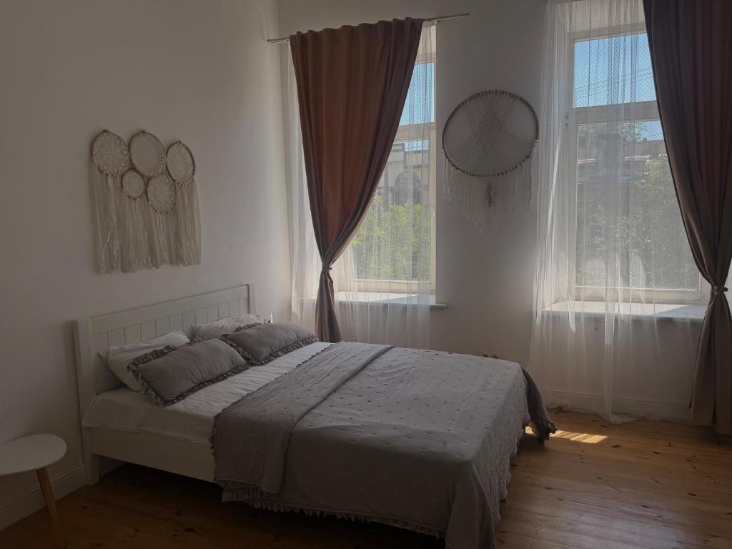 a bedroom with a bed in front of two windows at Belle Art Hotel in Odesa