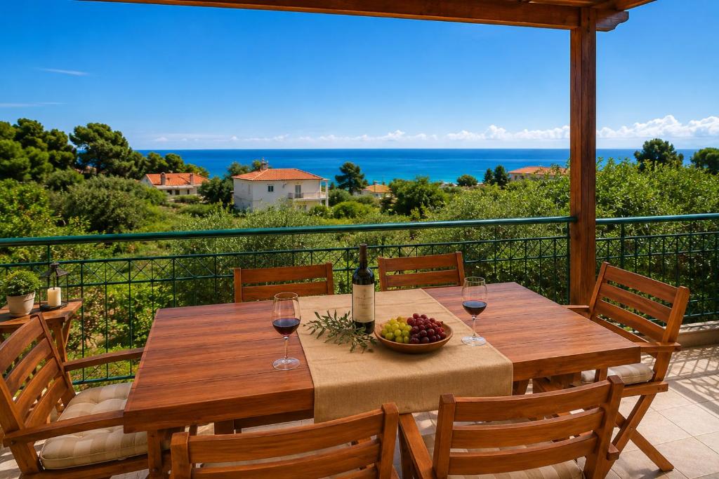 a table with wine glasses and a bowl of fruit on a balcony at E&M Villa Sea View II in Polychrono