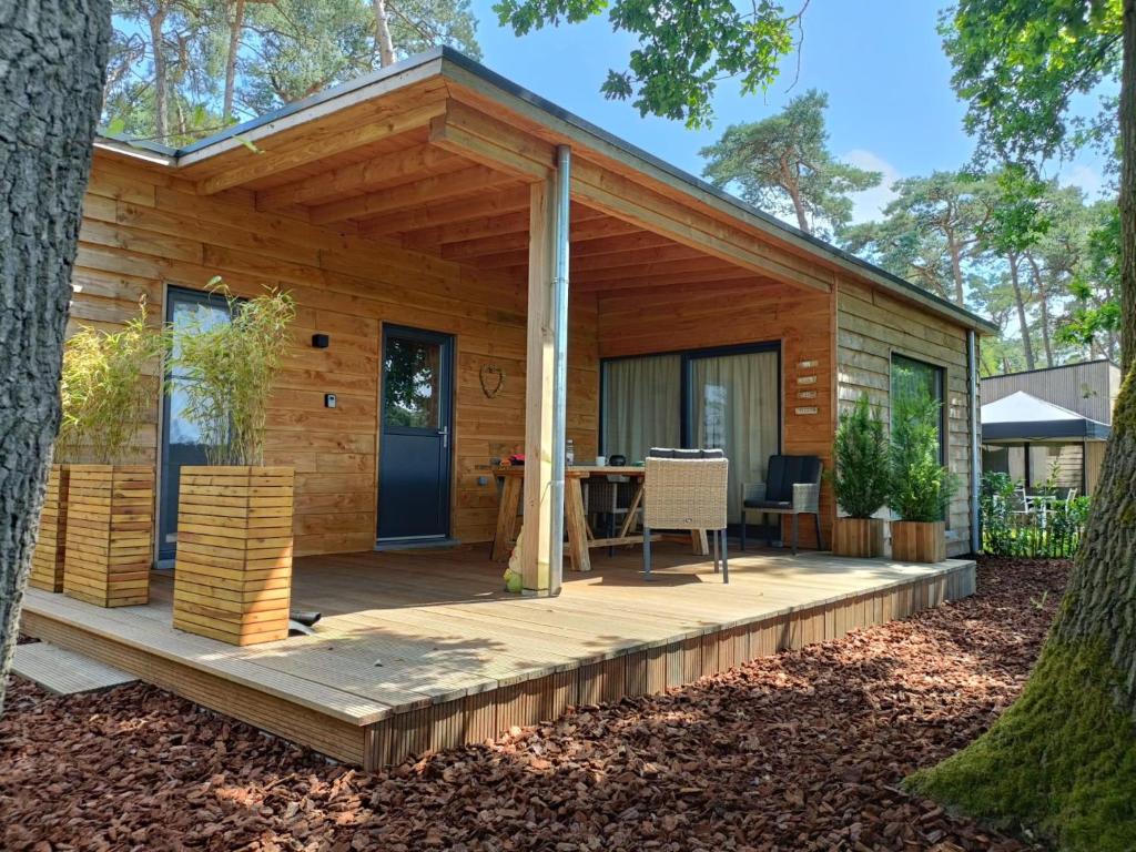 eine Holzhütte mit einem Tisch auf einem Deck in der Unterkunft Veldzicht in Bocholt