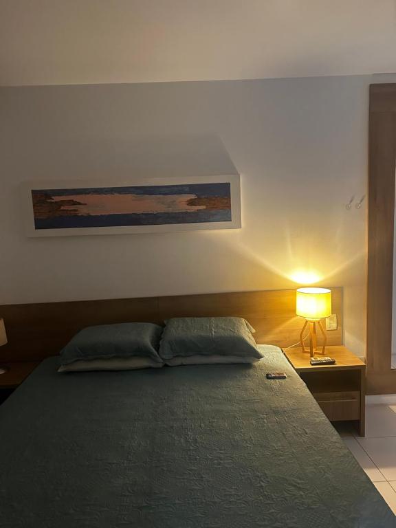 a bedroom with a bed and a lamp on a table at Diamond Flat Aparthotel REDE Mont Blanc in Nova Iguaçu