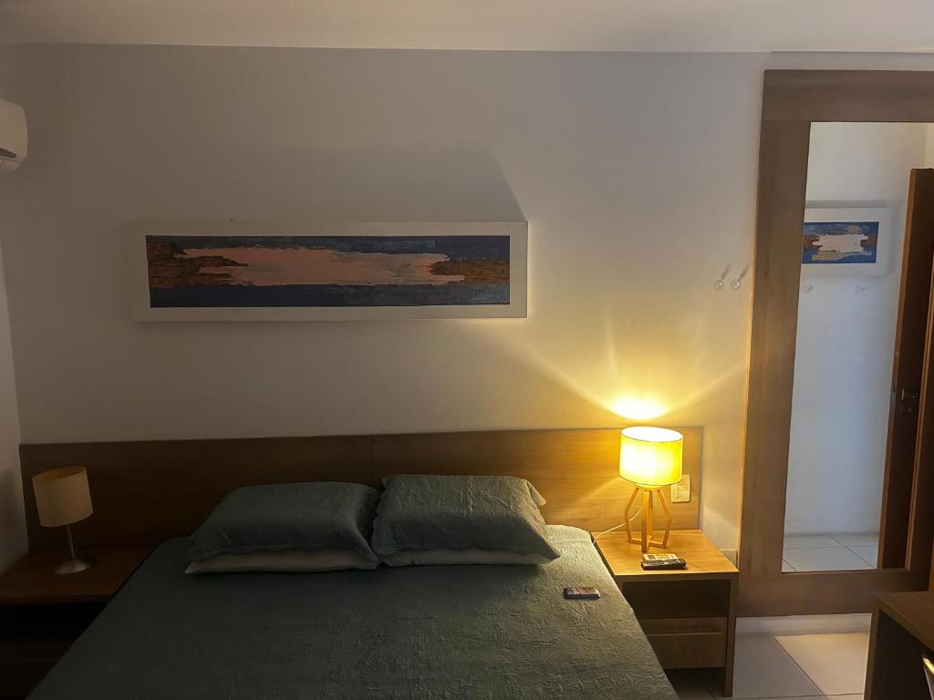 a bedroom with a bed with a lamp and a painting at Aparthotel diamond flat in Nova Iguaçu