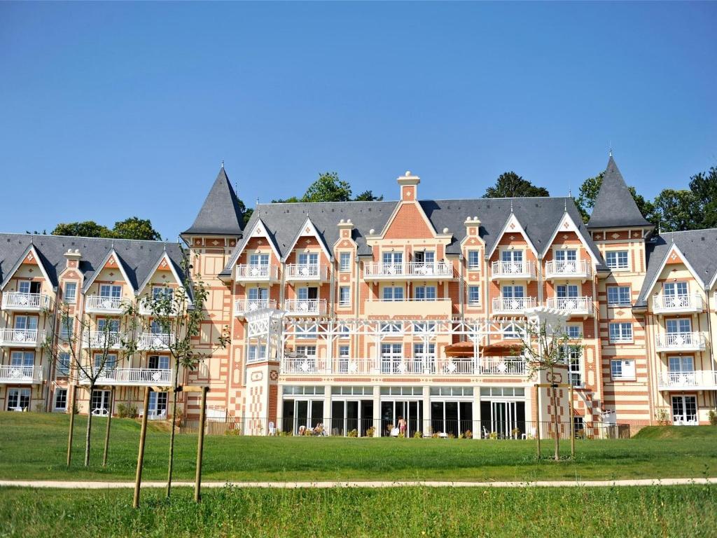 a large building on a field with trees in front at Tranquil Apartment with Pool Access in Bagnoles de l'Orne