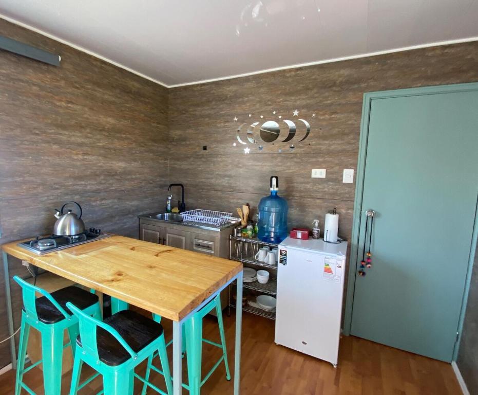 a kitchen with a wooden table and a refrigerator at Cielo Tiny House in San Pedro de Atacama