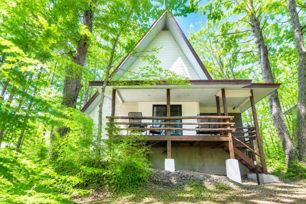 a tiny house in the woods with a porch at rinne 北軽井沢 Forest3 in Tsumagoi