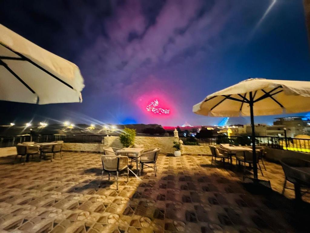 a patio with tables and umbrellas at night at House Pyramids View Hotel in Cairo