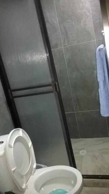 a bathroom with a toilet and a glass shower at Apartaestudios El Cable in Manizales