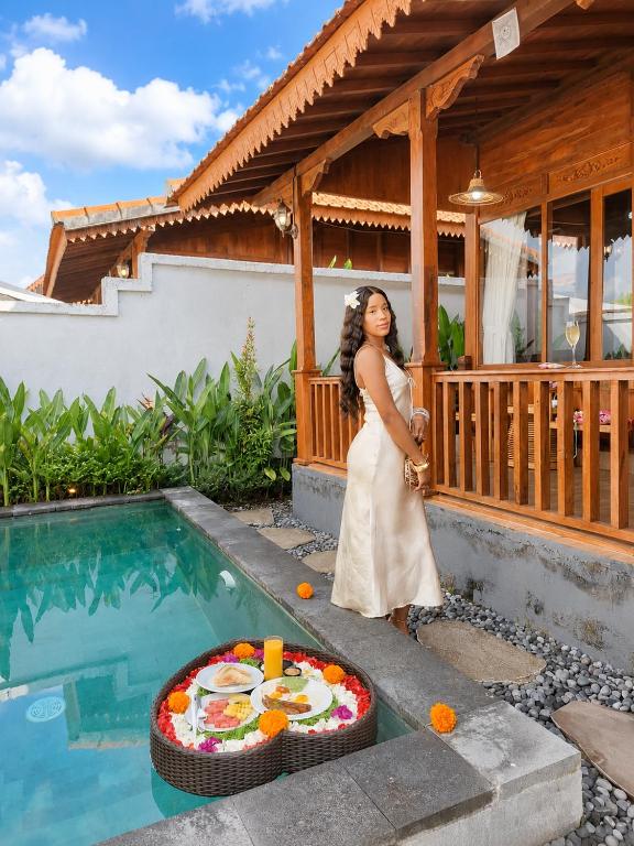a woman standing next to a pool with a cake at Pondok di Uma Villa Ubud in Ubud