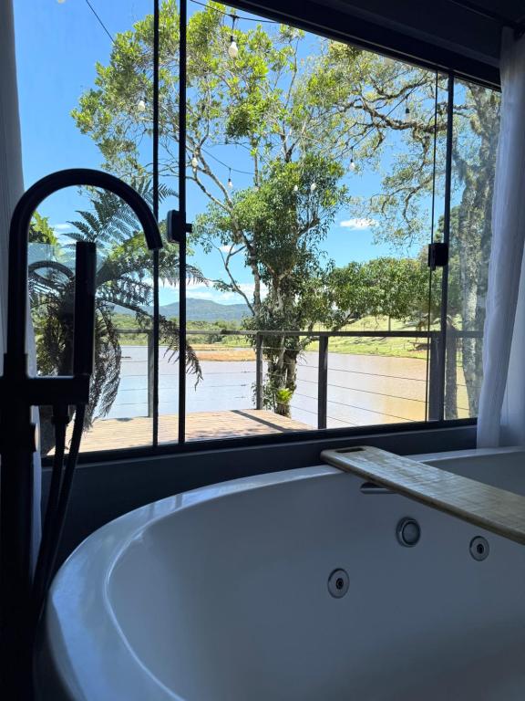 a bath tub in a bathroom with a window at Cabana do Lago com passeios a cavalo gratuito in Urubici