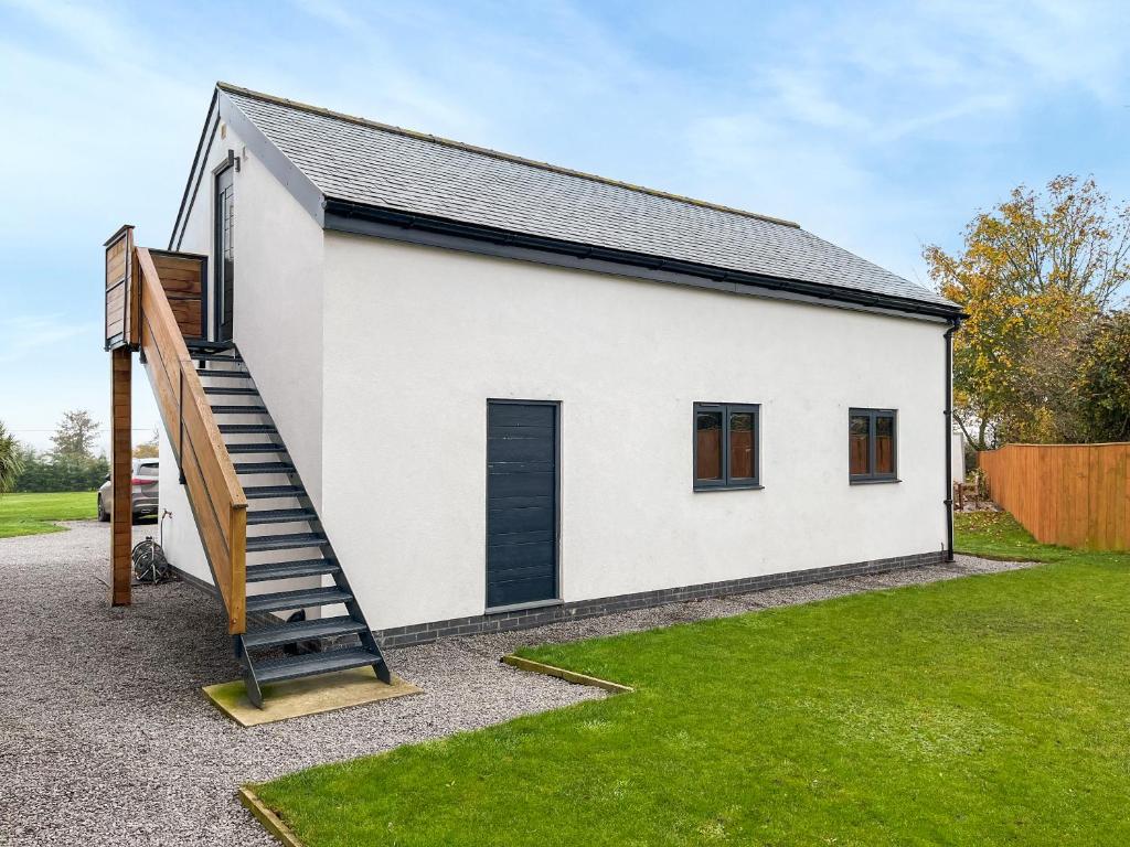 a white house with a staircase in a yard at Gatherley Loft in Scorton