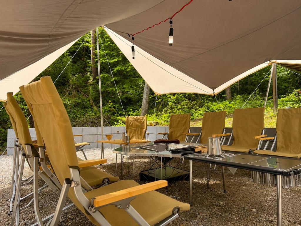 a group of chairs and tables under a tent at 1日1組様限定 最大10名様 キャンプ 温泉付き Villa 水と深緑 in Azumino