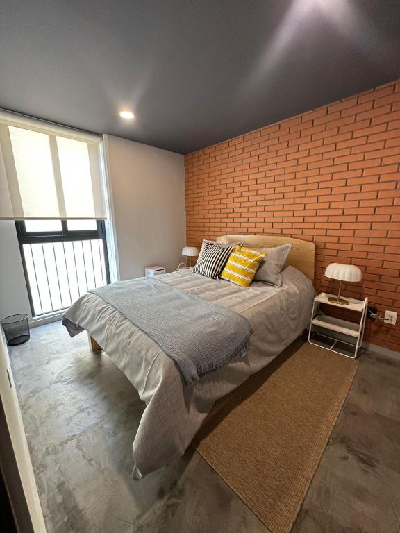 a bedroom with a large bed and a brick wall at Tradere in Guadalajara