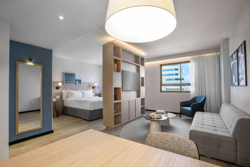 a living room with a couch and a bed and a mirror at Hotel Brasil 21 Suites, Affiliated by Meliá in Brasília