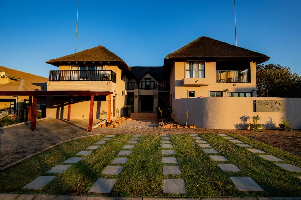 a house with a grass yard in front of it at Weavers Nest Guesthouse in Modimolle
