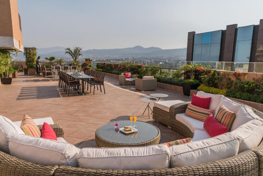 een patio met banken en tafels op een dak bij Suites Perisur Apartamentos Amueblados in Mexico-Stad