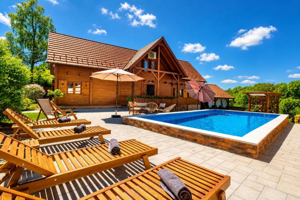 a house with a swimming pool and some wooden benches at Rustic Cottage With Heated Pool - Happy Rentals in Velika Buna