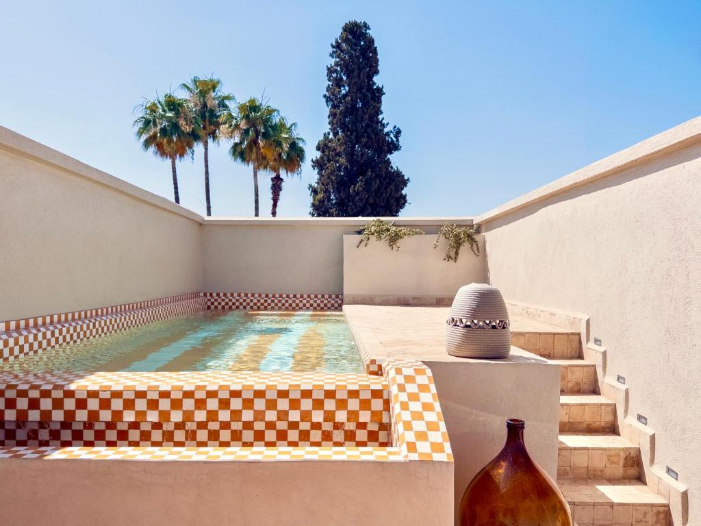 a swimming pool with a bench next to a house at Riad Djannaat Exceptional private riad pool staff in Marrakesh