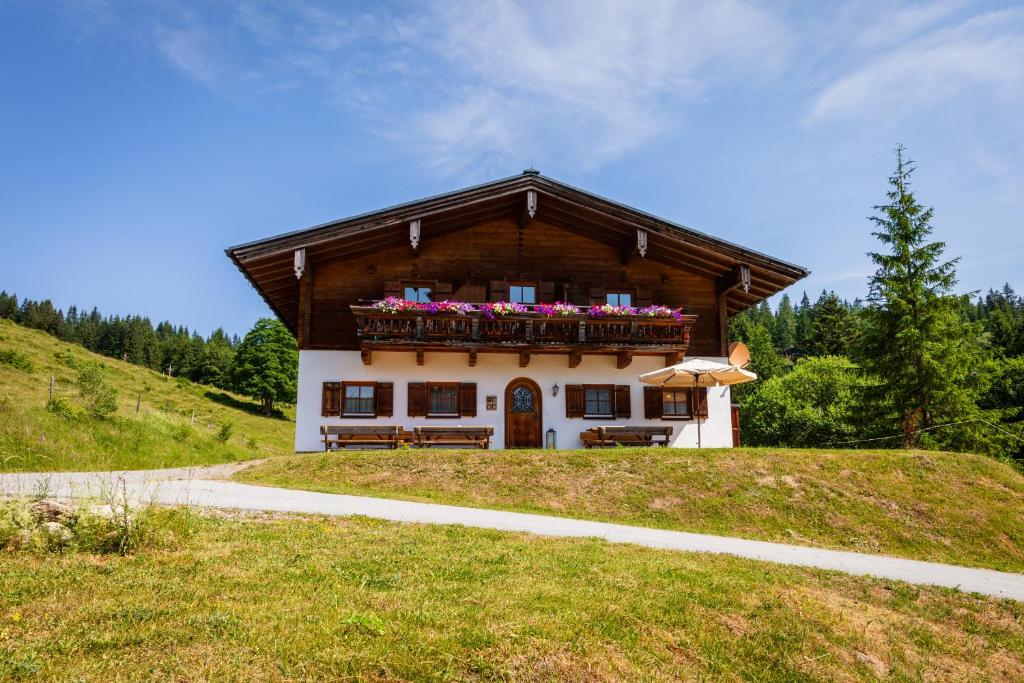 a house on a hill with a balcony with flowers at Haus Obweg - Postalm in Abtenau