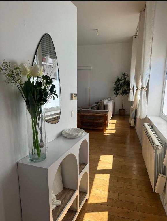 a living room with a vase of flowers and a mirror at La bulle dunkerquoise in Coudekerque-Branche