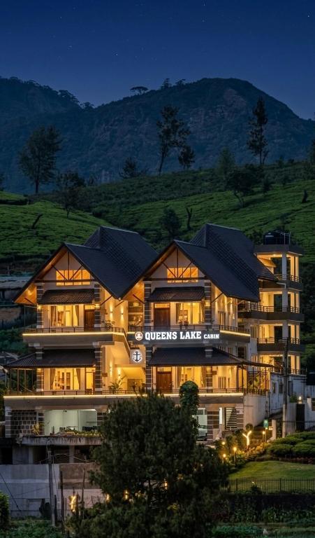 a large building with lights in front of a mountain at Queens Lake Cabin in Nuwara Eliya