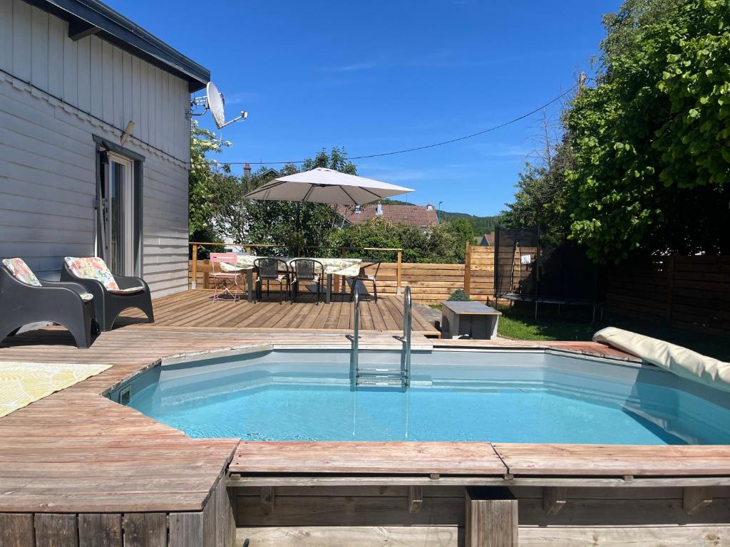 a small swimming pool with a deck and an umbrella at Villa 1950 piscine et spa- Gérardmer - terrain entièrement clos pour animaux in Anould