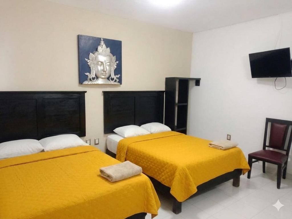 a hotel room with two beds with yellow sheets at Hotel Peccato Originale in Tuxtla Gutiérrez