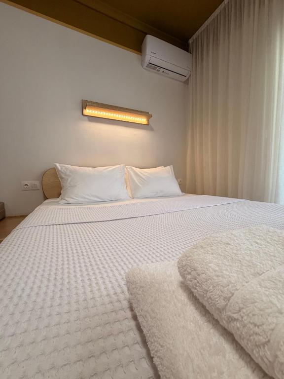 a bedroom with two beds with white sheets and a light at Aurora Suite in Xanthi
