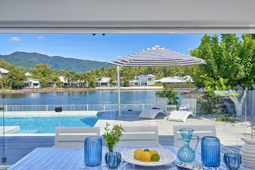 a patio with a table and an umbrella and a pool at Villa Aura - Private Pool - Lakefront & Near Beach in Trinity Beach